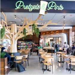 Pretzels and pints storefront with wooden tree, wooden chairs and string lights