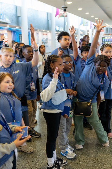 Children in blue t shirts raising their hands
